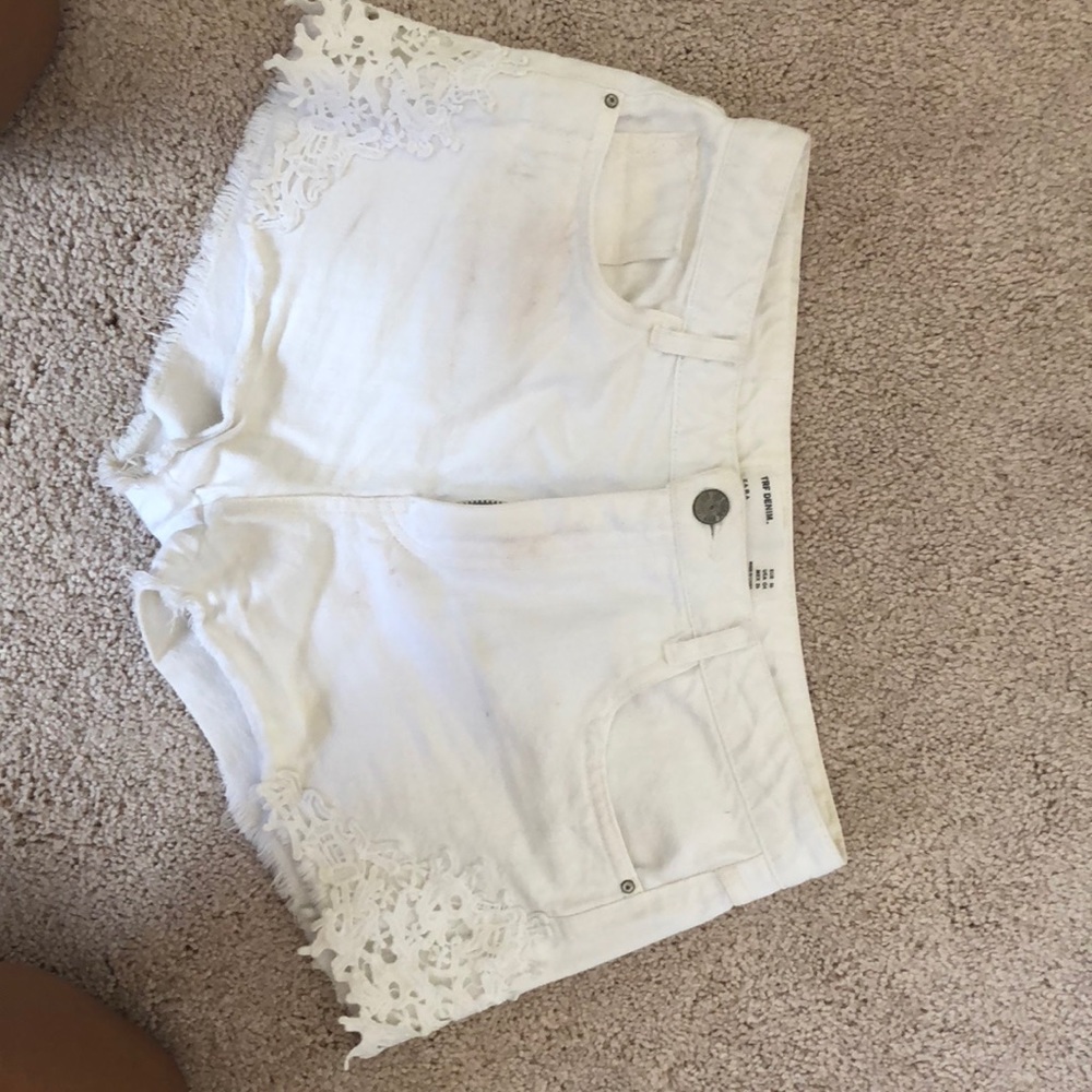 White jean shorts with lace on the sides.
